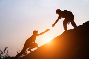 Dos persona ayudándose a subir una montaña como símbolo de la terapia de apoyo en Móstoles