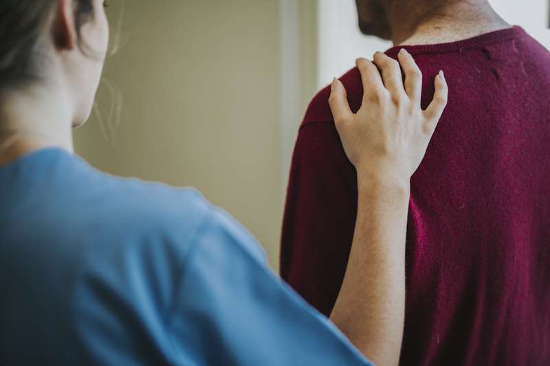 Imagen de una mujer apoyando a un paciente tocándole el hombro