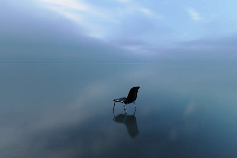 Silla sola en mitad del mar simulando la soledad
